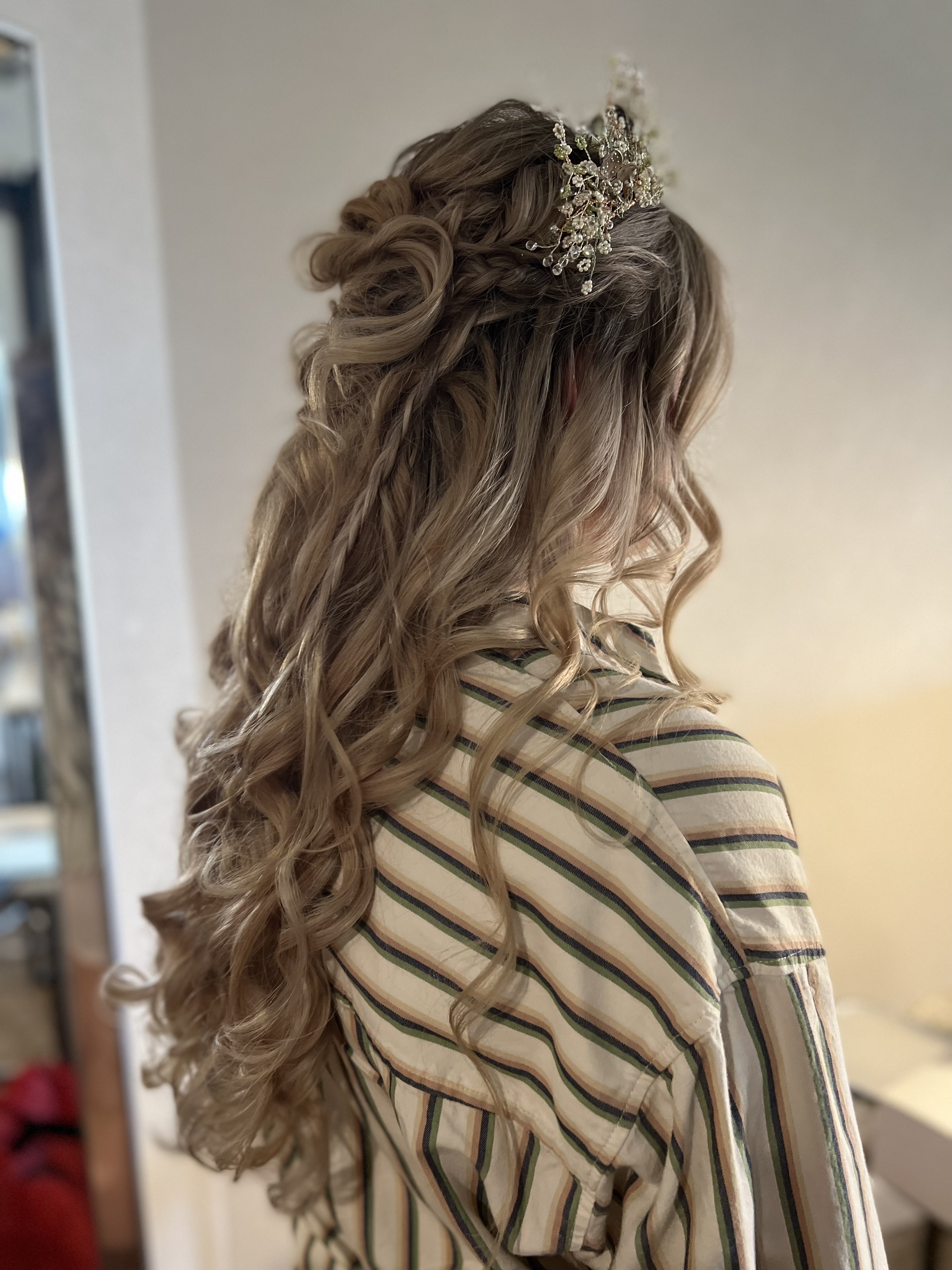 Bride's half-up wedding hairstyle with loose curls, a braid, and a floral hair comb
